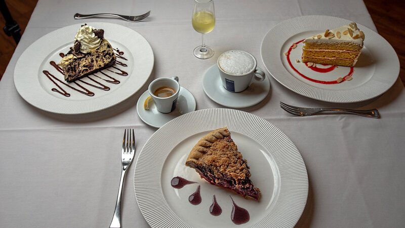 Multiple cake and pie desserts. Cappuccino, espresso and white wine.